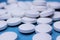 Medical round white tablets, calcium vitamins closeup on blue background with space for text or image. Pills