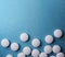 Medical round white tablets, calcium vitamins closeup on blue background with space for text or image. Pills.