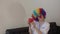 Medical sister in clown\'s wig shows red piggy bank to others.