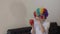 Medical sister in clown\'s wig shows red piggy bank to others.