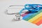 Medical stethoscope and lgbtq community flag on gray background copy space