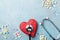 Medical stethoscope, red heart and drug pills on blue background top view. Healthy and blood pressure concept.