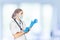 Medical surgeon doctor woman over blue clinic background. Doctor putting on sterile gloves. Place for medical advertise