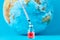 Medical syringe and ampoule with a medicine against Earth globe. ï¿½oncept of epidemic, virus and human infection