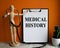 Medical table with a wooden person along with a stethoscope. Inscription MEDICAL HISTORY on the clipboard with the holder. Health