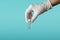 Medical theme: a doctor`s hand in a white medical glove holds a vial of injection medicine or coronavirus vaccine. side view.