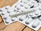 Medical thermometer and tablets in silvery blisters on a wooden table.