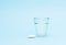Medical white capsule tablet and glass water blue background