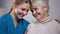 Medical worker hugging and supporting smiling elderly lady in nursing home