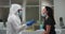 Medical worker in protective clothing taking swab test from female patient