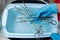 A medical worker rinses surgical instruments in a tray of water.