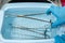 A medical worker rinses surgical instruments in a tray of water.