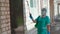 Medical worker spraying antiseptic spray on hospital door and brick wall. Treatment of building with antiseptic solution