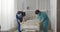 Medical workers in safety mask and gloves changing bed sheets in hospital room