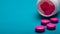 Medication bottle and bright pink pills spilled on dark blue coloured background. Medication and prescription pills close up.