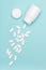 Medication bottle and white pills spilled on blue pastel colored background. Medication and prescription pills flat lay background