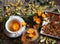 Medicinal autumn background. Herbal healthy marigold tea with a teapot, dried and fresh flowers on a wooden background with autumn