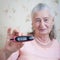 Medicine, age, diabetes, health care and people concept - senior woman with glucometer checking blood sugar level at