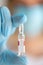Medicine ampoule for injection in nurse hand. Medical glass vial for vaccination. Science equipment, liquid drug or vaccine
