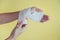 Medicine bandage on injury female hand on yellow background