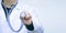 Medicine doctor in a white medical coat holds with hand a stethoscope. Copy space for text or banner