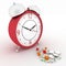 Medicine pills and red retro alarm clock