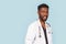 Medicine, profession and healthcare concept. African american male doctor with stethoscope in white coat on blue background