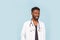 Medicine, profession and healthcare concept. African american male doctor with stethoscope in white coat on blue background