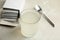 Medicine sachets, glass of water and spoon on light table