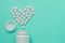 Medicines white, round heart shaped pills isolated on turquoise background.