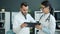 Medics in white gowns using tablet at work talking using gadget in office