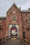 Medieval Ammersoyen Castle with its richly decorated entrance, brick walls and wooden bridge on cloudy day.