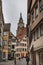 Medieval architecture: people in a medieval narrow alleyway with Stiftskirche St. Georg (Saint George Church) bell tower
