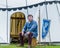 A medieval armorer sits outside his tent