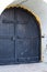 Medieval black door with metal in white wall of church