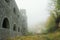 Medieval castle and fort with arch windows in misty and foggy morning on a hill.