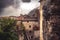 Medieval cityscape with tile roofs and ancient building facade in front of dramatic sky with antique architecture in old European