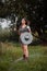 A medieval female warrior dressed in chain mail with a sword and shield in her hands poses against the background of a forest.