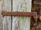 A medieval iron hinge attached to a rough plank door set into a rock building