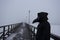 Medieval plague doctor stands on winter wooden bridge