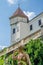 Medieval sculpture surrounded by green in front of beautiful restored white castle and blue sky in Czech Republic