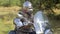 A medieval warrior in chain mail and a helmet sits at the wheel of a motorcycle against the backdrop of the forest.