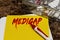 Medigap is written in red letters on a yellow sheet lying on the table next to a box of pills