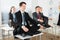 Meditating businesspeople sitting on desk