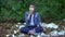 Meditating woman putting on protective mask sitting park landfill, air pollution