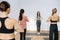 Meditating women do yoga in a group in front of an instructor, starting exercise