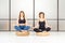 Meditating women sitting in the lotus pose with closed eyes in the white room. It`s yoga time.