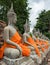 meditation buddha statues along the wall with monk robe decoration