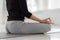 Meditation while doing lotus pose. A woman is sitting on gray mat and practicing yoga in class.