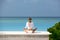 Meditation. Photo of a woman who is sitting in the lotus position on the ocean coast. Maldives